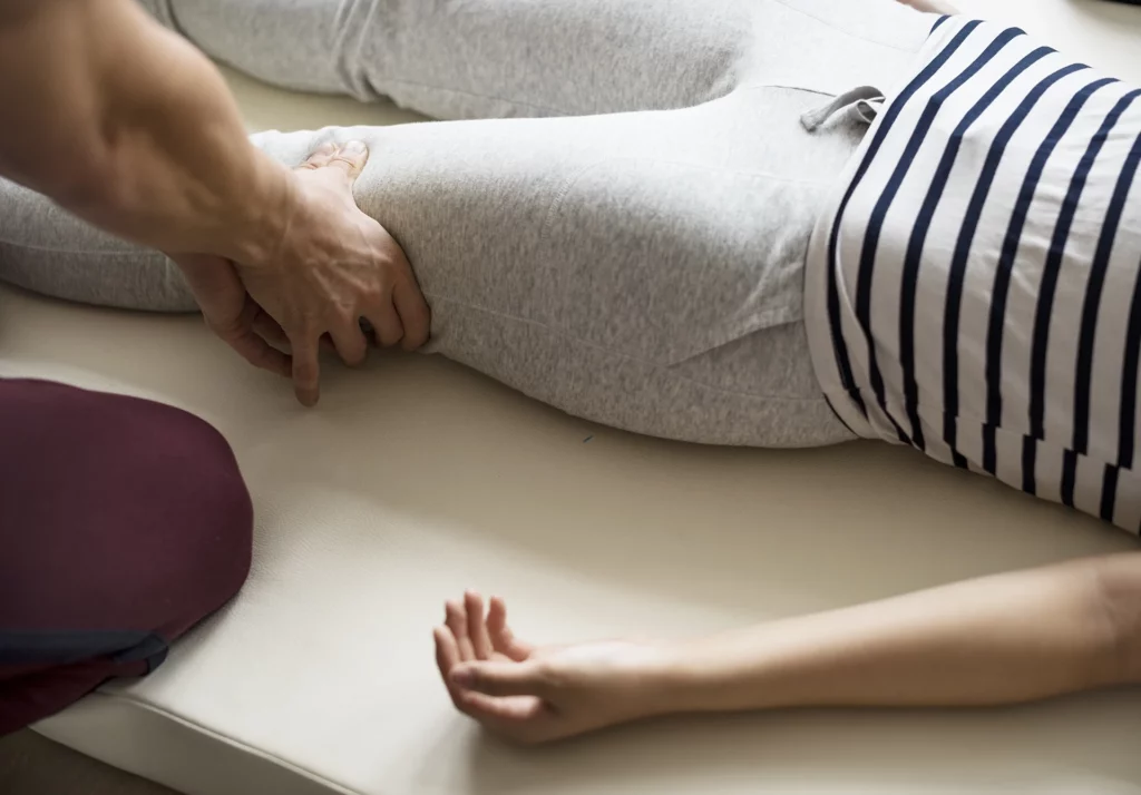Physiotherapist performing manual therapy on the patient's hip and thigh for pain relief. Myofascial release in South East Melbourne.